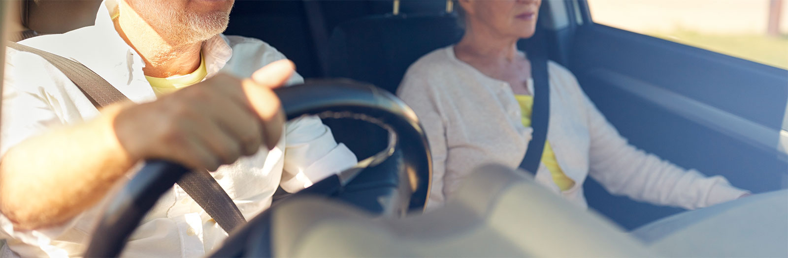 Close up of older man driving with a woman passenger